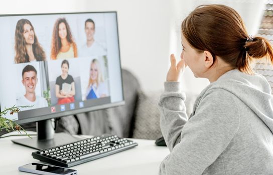 Girl during remote educaton class via video link with friends classmates. Teenager e-learning with computer at home in coronavirus pandemic time