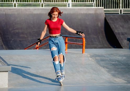 Beautiful girl on roller skates at park ramp. Female teenager rollerskating at summer outdoors