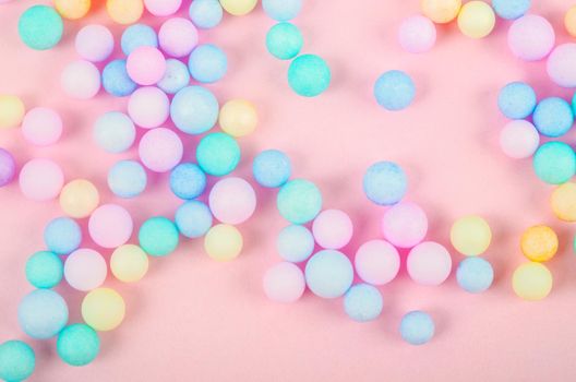 The Foam beads of various colors brightly colored on pink pastel background.