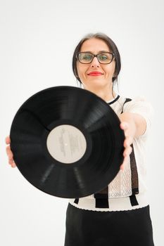 Studio photo of middle aged woman starting getting grey-haired wearing black and white clothes with vinyl record in hands on white background, middle age sexy lady, happy life concept.