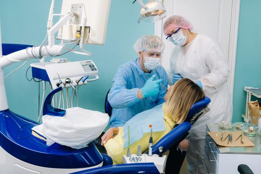 A female patient in dental glasses treats teeth at the dentist with ultraviolet light. dental fillings.