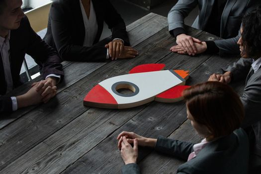 Team of business people with rocket as a sumbol of high risky goals targets success at meeting table