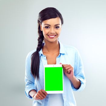 Shot of a young woman presenting a digital tablet over a grey background.