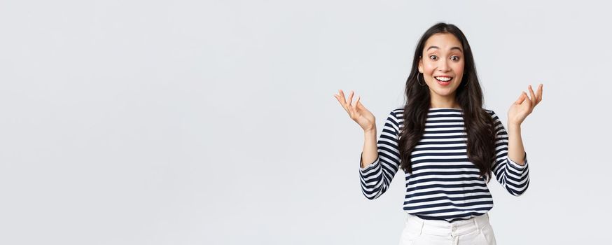 Lifestyle, beauty and fashion, people emotions concept. Surprised and amazed happy smiling asian woman find out perfect news, raise hands up astonished, congratulating or praising friend.