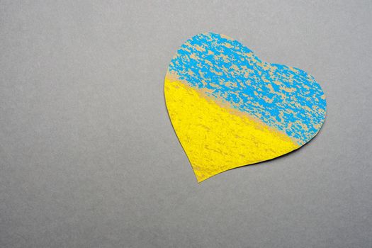 Save Ukraine sign support concept heart shape love UA. National symbol ukraine painted child drawing heart isolated on gray background. No war kids making symbol heart Ukraine flag painted yellow blue