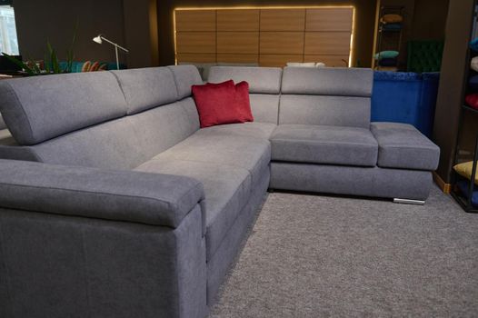 Upholstered furniture displayed for sale in the showroom of furniture store. Modern stylish sofas, couches and settees with bright colored cushions from high quality fabrics in the exhibition hall.