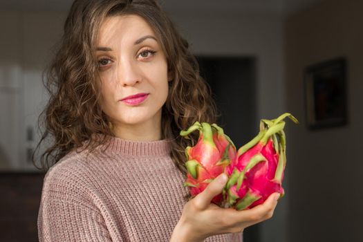 Young girl is holding two fresh ripe organic dragon fruits or pitaya, pitahaya. Exotic fruits, healthy eating concept.