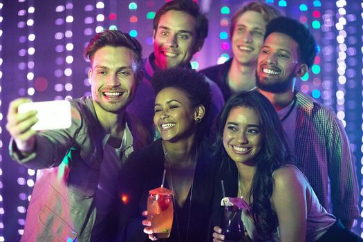 Shot of a happy group of friends taking a selfie with a smartphone in a nightclub.