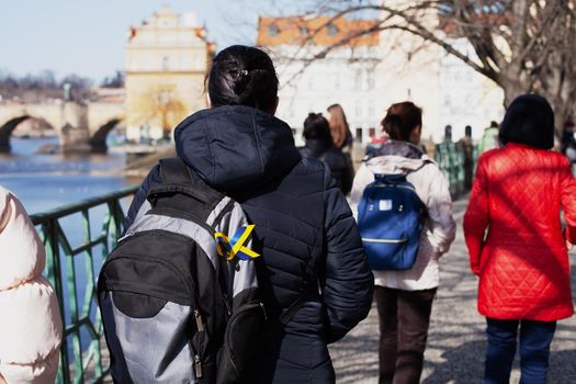 Ukrainian refugees in Europe. Women from Ukraine walk along the street of a European country. Woman with backpack with Ukrainian flag ribbon.