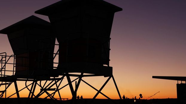 Lifeguard stand, hut or house on ocean beach after sunset, California coast, USA. Life guard tower or station silhouette in twilight dusk. Contrast beachfront watchtower for surfing safety on shore.