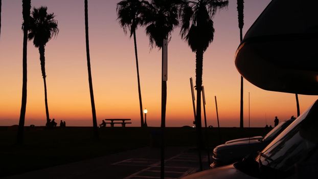 Motorhome trailer, caravan for road trip, palm trees on beach at sunset, California coast, USA. Camper van RV motor home in beachfront park at sundown, San Diego, Mission beach. Mobile home campervan.