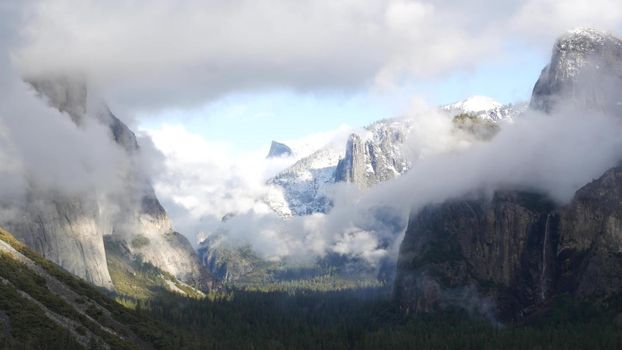 Foggy mountain, bare cliff or rocks, misty autumn weather, Yosemite valley, California USA. Scenic crags, bluff and fall forest. Brume or haze clouds dramatic timelapse. Tunnel view near Glasier point