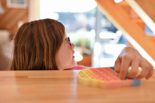 A girl plays with a colorful antistress sensory toy fidget push pop it