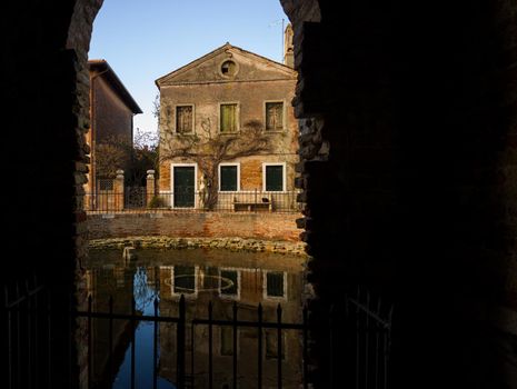 View of Italian dwelling through arched masonry passageway in Torcello, Italy