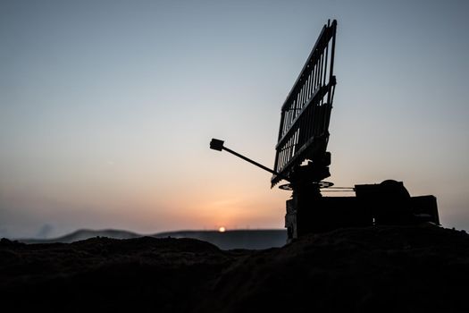 Creative artwork decoration. Silhouette air defence radar antenna during sunset. Satellite dishes or radio antennas against evening sky. Selective focus