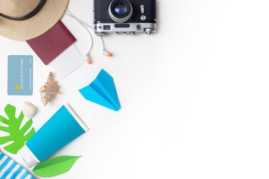 Summer travel accessories set top view: passport, camera, straw hat, sunscreen, headphones, credit card , seashell, paper airplane lies on a white background. Copy space.