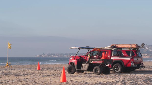 Lifeguard red pickup truck, life guard auto on sand, California ocean beach USA. Rescue pick up car on coast for surfing safety, lifesavers 911 vehicle, sky and sea waves. Seamless looped cinemagraph.