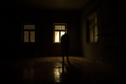 Horror silhouette inside abandoned creepy room with window at night. Horror scene. Halloween concept.