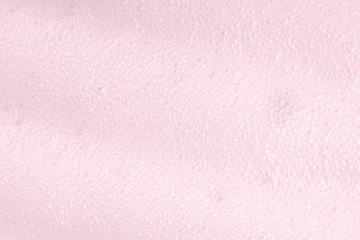 Pink foam macro background with bubbles. Soapy surface closeup. Foamy cleansing skin care product texture from soap, detergent, shampoo, shaving foam or cleanser. Laundry spume