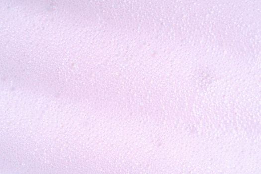 Purple laundry spume. Foam macro background with bubbles. Soapy surface closeup. Foamy cleansing skin care product texture from soap, detergent, shampoo, shaving foam or cleanser.