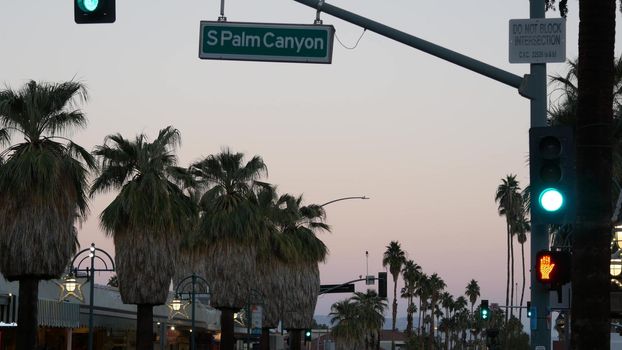 Palm trees and sky, Palm Springs street, city near Los Angeles, semaphore traffic lights on crossroad. California summer road trip on car, travel USA. Road sign Palm canyon, twilight dusk after sunset