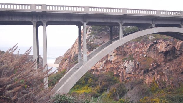 Arch bridge over river creek in canyon, pacific coast highway scenic road, California road trip, Big Sur nature, USA. Cabrillo highway 1, tourist route along ocean. Steep cliffs or rocks under viaduct