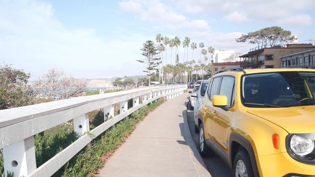 Waterfront or beachfront promenade with palmtrees. Yellow car and palm trees, Rocky Point in La Jolla, San Diego, California coast, USA. Summer tropical boardwalk aesthetic. Waterside city street.