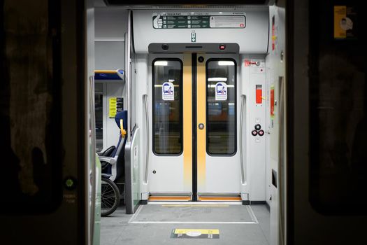 Doors of wagon in railway station of Milan, electric train carriage interior with an open sliding mechanical door at a train station platform. Milan, Italy - December 15, 2020