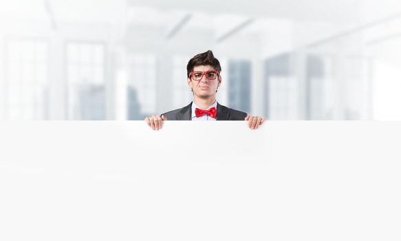 Young businessman holds a banner in front of him with two hands. Place for text