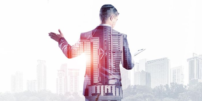 Businessman pointing on empty space on background modern cityscape. Standing entrepreneur in business suit and tie without face. Double exposure business template. Success and trade concept