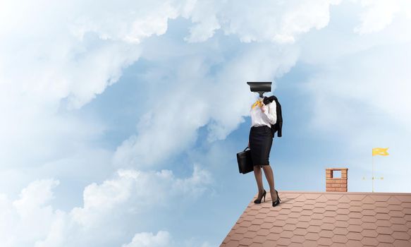 Faceless businesswoman with camera zoom instead of head standing on house roof