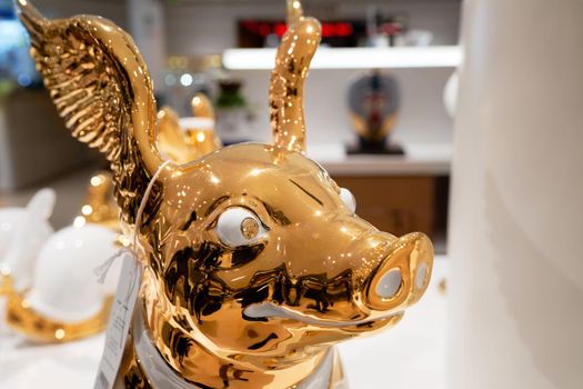 Golden pig statue in Rinascente, collection of high-end stores with Italian and international brands in fashion, accessories, design. Milan, Italy - December 15, 2020