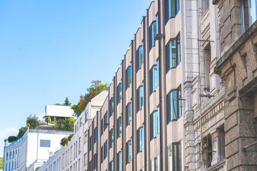 Plants and trees on the top of the modern buildings in center of european city. Green terrace on the roof of the house. City center on sunny summer day. Cityscape of Milan.