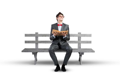 Student sits on a bench, holding a book. Traditional education concept