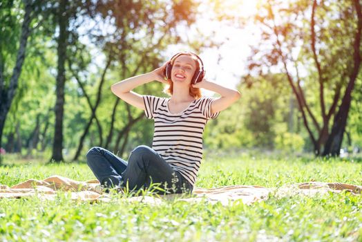 Young attractive woman listens to music in the park. Enjoying music in the park