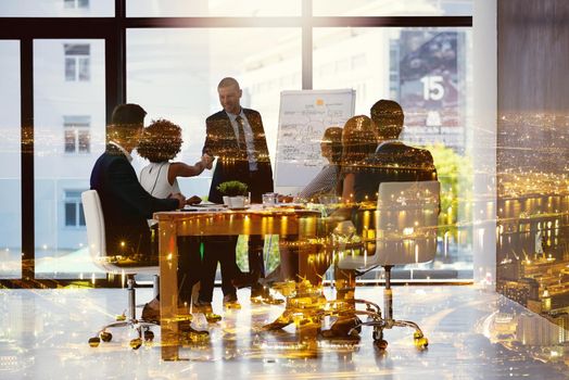 Multiple exposure shot of two businesspeople shaking hands during a meeting superimposed over a cityscape.