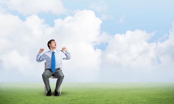 young businessman yawns and stretches while sitting on a chair