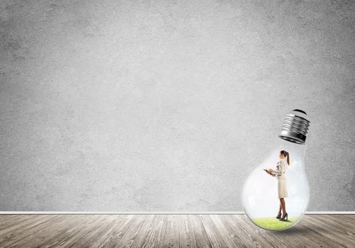 Businesswoman inside of light bulb in empty concrete room