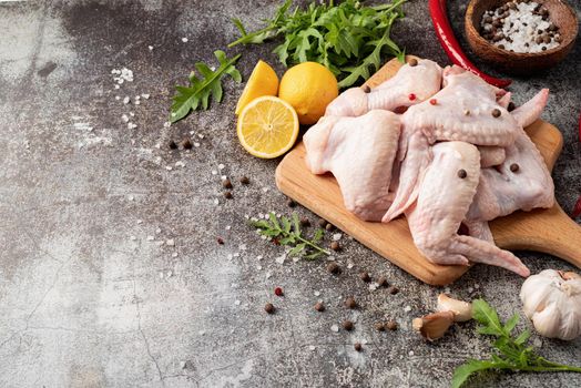 Sliced chicken wings with skin on a cutting board. Dark background with copy space