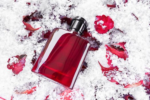 Perfume bottle on red leaves covered by snow background. Packaging design mockup. Branding identity. Top view, flat lay.