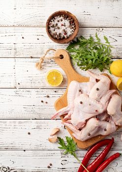 Sliced chicken wings with skin on a cutting board. White wooden background with copy space