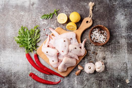 Sliced chicken wings with skin on a cutting board. Dark background with copy space