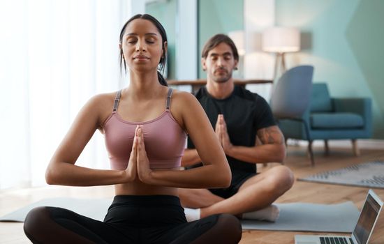 Cropped shot of an athletic young couple meditating during their workout at home.