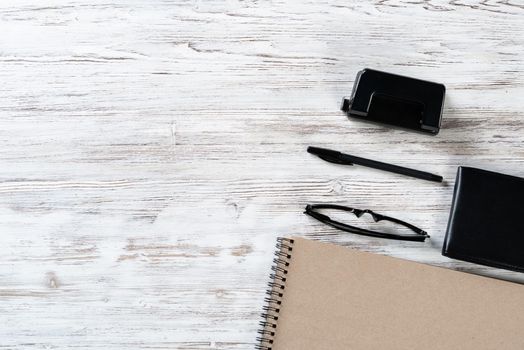 Still life of modern office workspace with supplies. Spiral notepad and paper hole puncher on white wooden surface. Time management and day planning. Education, freelance and business concept.