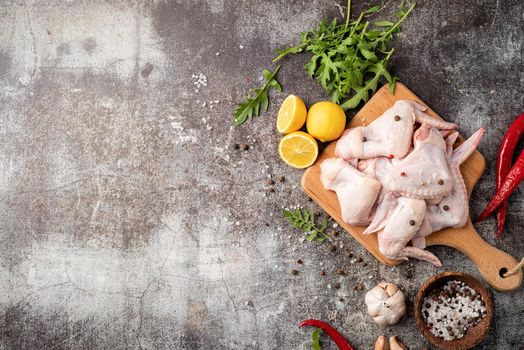 Sliced chicken wings with skin on a cutting board. Dark background with copy space