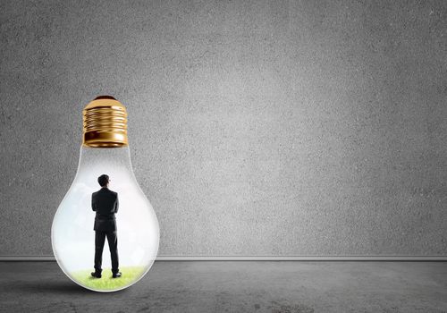 Businessman inside of light bulb in empty concrete room