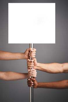 Studio shot of unidentifiable hands holding on to a poster against a gray background.