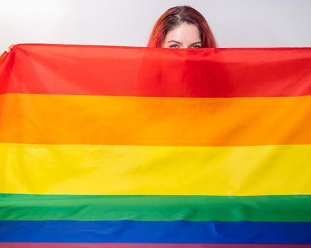 Caucasian woman holding lgbt flag covering herself