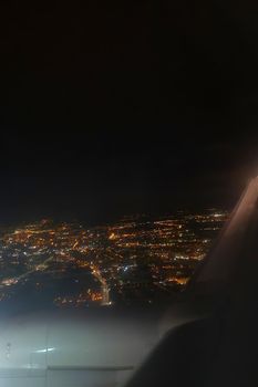 View of the night glowing city from a flying plane