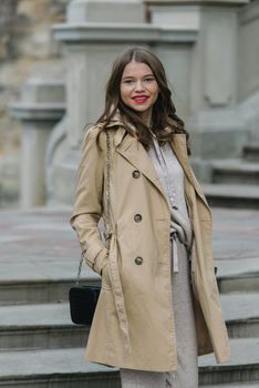 Portrait of fashionable women in beige sports suit and trench coat posing. street look fashion